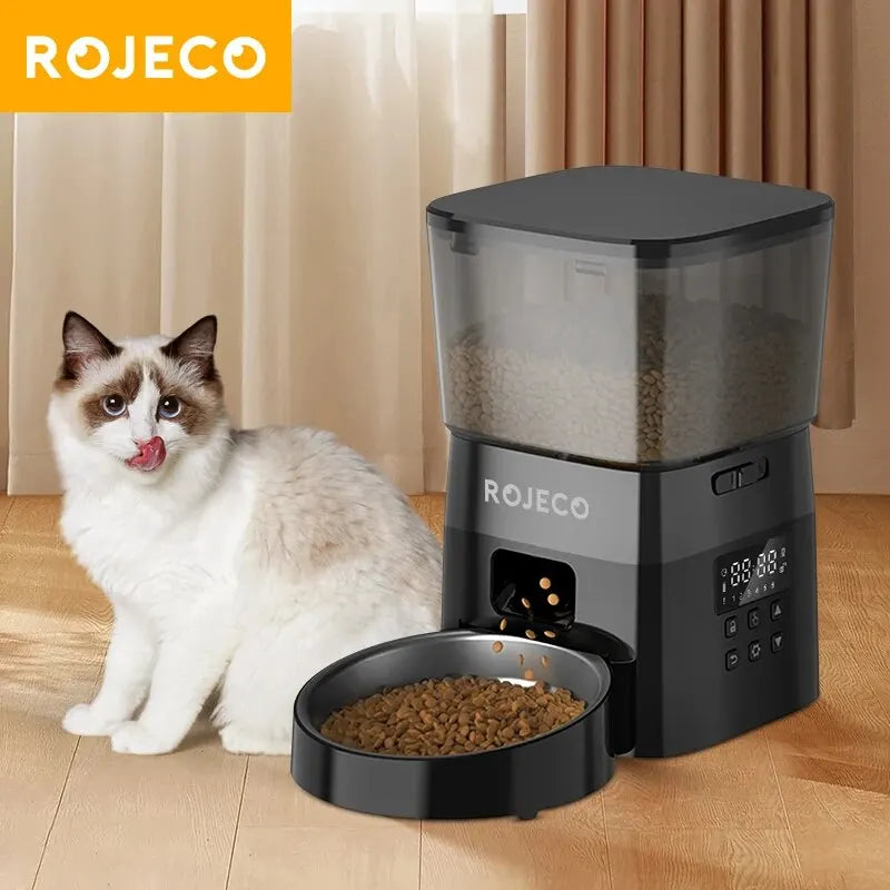 SmartServe automatic cat feeder in black with a cat waiting beside the stainless steel bowl